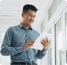 Asian business man smiling while looking at a tablet. 