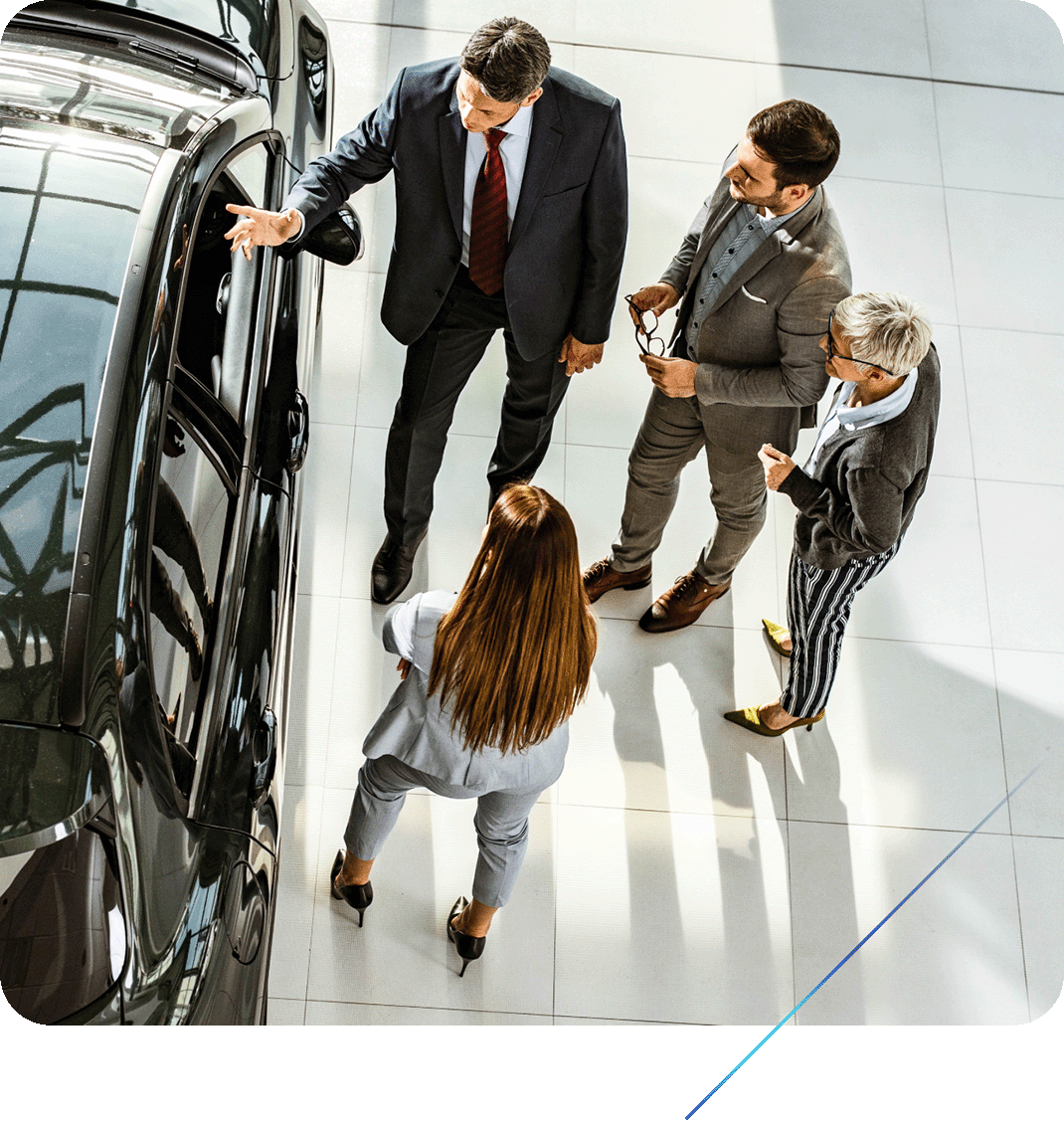 Four people discussing a small SUV inside a car dealership.