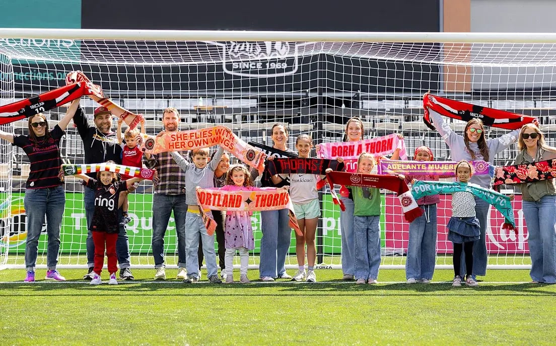 Portland Thorns FC fans and families holding team scarves together on the soccer field