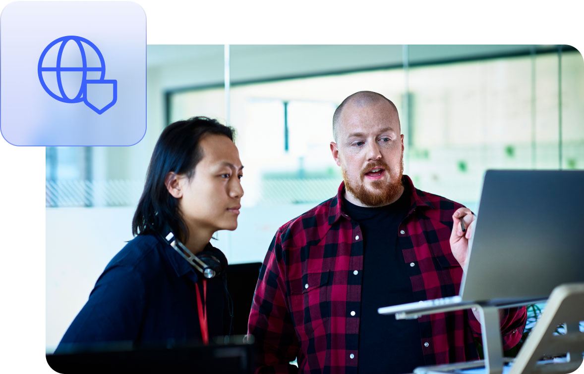 Two people discussing information on a laptop at a standing desk.
