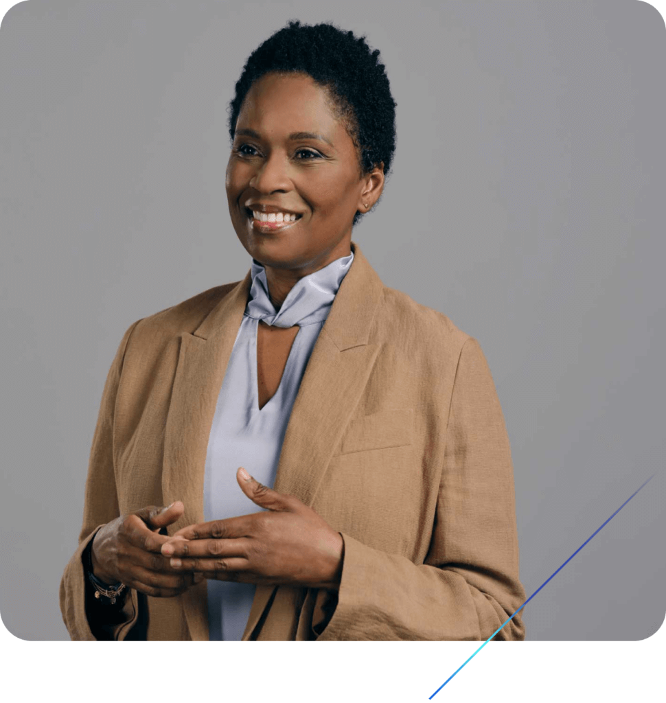 Smiling businesswoman in blazer standing with hands together, conveying confidence.